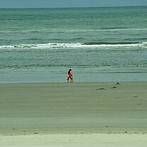Frau mit Kindern spazieren am Strand
