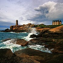Haus u. Leuchtturm mit spritzender Gischt